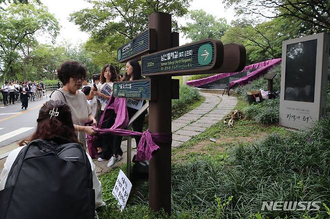 [서울=뉴시스] 권창회 기자 = 4일 오전 서울 중구 남산 기억의 터에서 정의기억연대를 비롯한 여성단체 회원들이 서울시 기억의 터 기습철거 규탄 행동의 일환으로 보라색 띠를 두르고 있다. 2023.09.04. kch0523@newsis.com