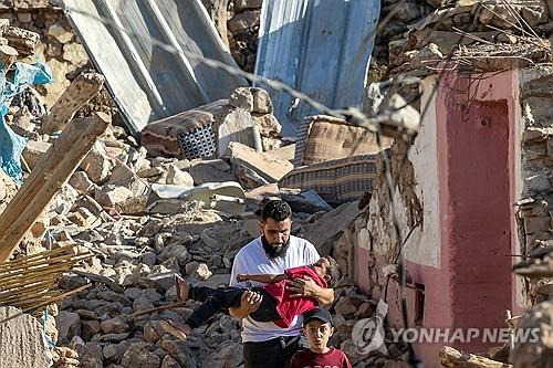 무너진 건물 잔해에서 한 소년을 구해 나오는 모로코 남성. [AFP 연합뉴스 자료사진]