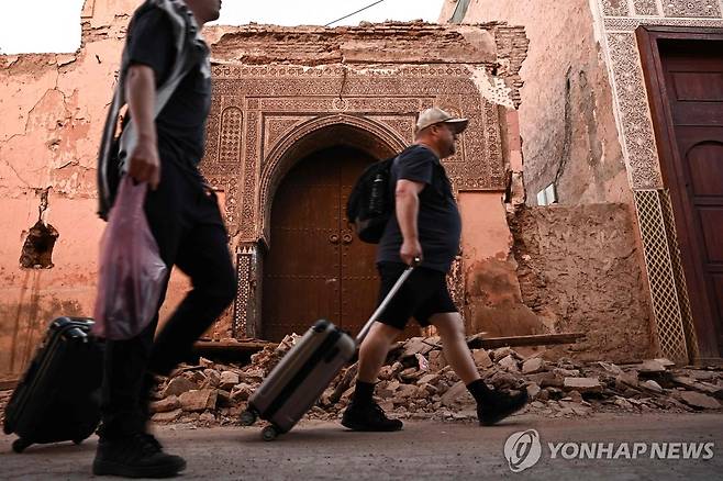 규모 6.8 강진에도 끊이지 않는 관광객들의 발길 (마라케시[모로코] AFP=연합뉴스) 모로코에서 규모 6.8의 강진이 발생한 지 사흘째인 10일(현지시간) 관광객들이 중세 역사 도시 마라케시의 손상된 건물 사이로 여행 가방을 끌고 가고 있다. 이날 미국 뉴욕타임스(NYT)는 마라케시에서 외국인 관광이 재개됐다면서 일부 관광객들이 다시 유명 관광지에 줄을 서기 시작했다고 보도했다. 2023.09.11 besthope@yna.co.kr