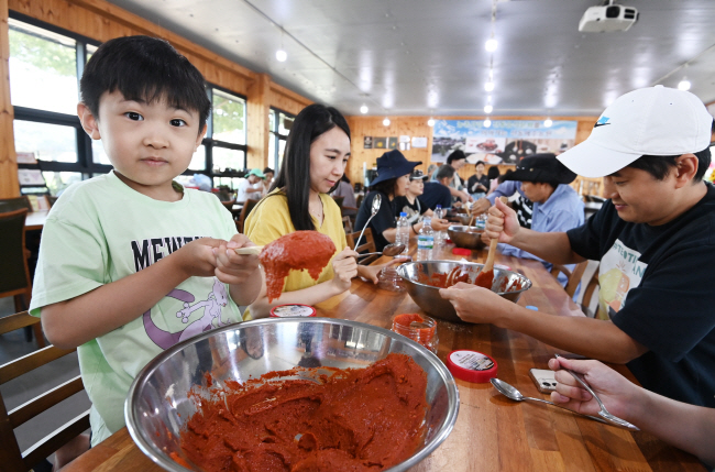 지난 10일 충북 음성군 선돌메주농원 조리실에서 ‘음성니나농, 사계절 농촌 탐사대-가을 랩소디’ 여행 투어에 참가한 박수혁(7·왼쪽 첫 번째) 군이 가족과 고추장 만들기를 하며 즐거운 표정을 짓고 있다.  박윤슬  기자