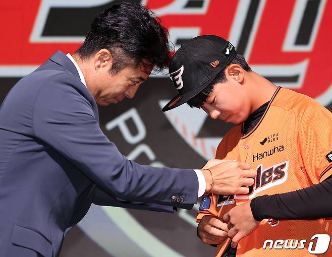 14일 오후 서울 중구 웨스틴조선호텔 그랜드볼룸에서 열린 ‘2024 KBO 신인 드래프트’에서 손혁 한화 이글스 단장이 전체 1순위로 황준서(장충고)를 지명한 뒤 유니폼을 입혀주고 있다. 2023.9.14/뉴스1 ⓒ News1 김진환 기자