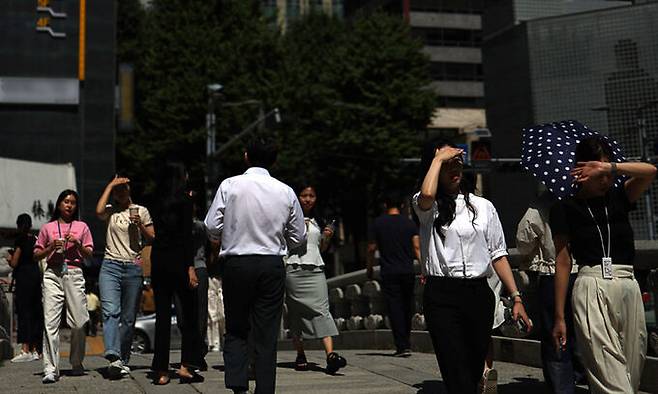 서울 종로구 청계천 인근에서 직장인들이 햇빛을 가리며 이동하고 있다. 연합뉴스