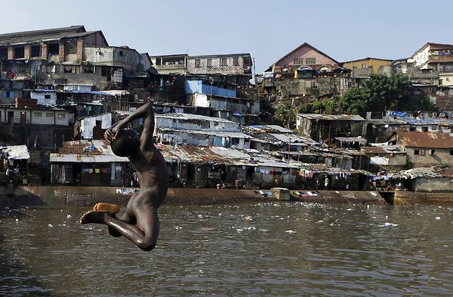 시에라리온 수도 프리타운의 물가에 위태롭게 형성된 빈민가에서 한 소년이 알몸으로 물에 뛰어들고 있다. 프리타운/AP 연합뉴스
