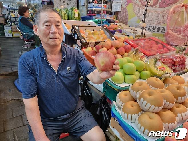 추석 명절을 아흐레 19일 경기 구리시 구리전통시장에서  과일장수 박석규씨(70)가 가판대에 진열돼 있는 사과를 들고 있다.박씨는 사괏값이 평년 대비 두 배 이상 급등하면서 팔리지 않는다고 토로했다.2023.09.19./뉴스1 양희문 기자