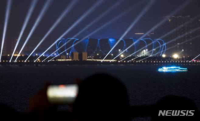 개막 하루 앞둔 2022 항저우 아시안게임.[항저우=뉴시스] 정병혁 기자 = 2022 항저우 아시안게임 개막을 하루 앞둔 지난 22일 중국 항저우 CBD파크를 찾은 시민들이 올림픽 스포츠센터 스타디움과 주변 건물 일대에 펼쳐지는 라이트쇼를 바라보고 있다. 2023.09.22. jhope@newsis.com