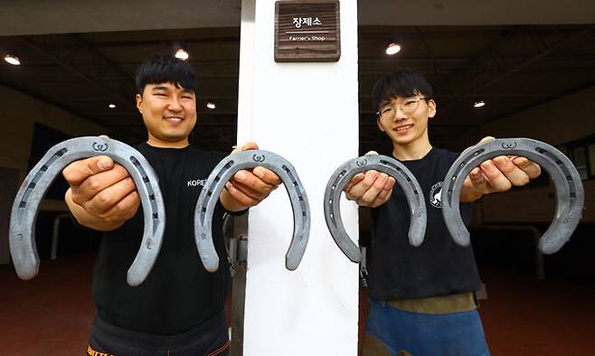 한국마사회 장원 장제사와 김정연 교육생이 장제소 앞에서 편자를 들어 보이고 있다.