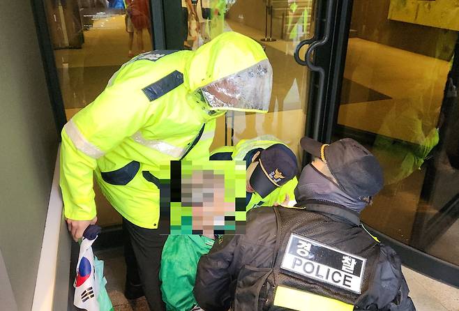 26일 서울 중구에 위치한 코리아나호텔 입구 앞에 앉아있는 80대 노인 A씨와 경찰들. A씨는 이날 급성 고혈압 탓에 길에 쓰러졌으나 군과 경찰이 곧바로 조치해 큰 사고는 발생하지 않았다. /최정석 기자