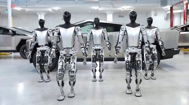 테슬라 공장 내 사이버트럭 앞에서 옵티머스 5대가 걷고 있다. 출처=테슬라 유튜브