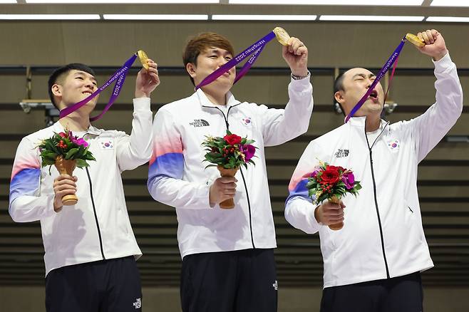 26일 중국 항저우 푸양 인후 스포츠센터에서 열린 제19회 항저우 아시안게임 남자 10ｍ 러닝타깃 혼합 단체전에서 금메달을 딴 한국 곽용빈(왼쪽부터), 정유진, 하광철이 시상대에 올라 메달을 들어 올려 보이고 있다. /연합뉴스