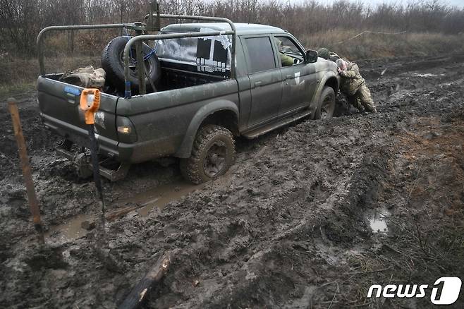 지난해 12월17일 (현지시간) 우크라이나 도네츠크 전선에서 병사들이 진흙탕에 빠진 차량을 밀고 있다. ⓒ AFP=뉴스1 ⓒ News1 우동명 기자