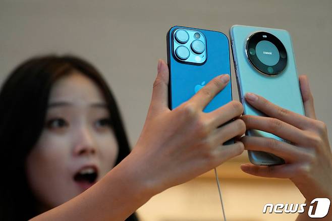 22일(현지시간) 아이폰15 시리즈 신제품 출시 첫날 중국 상하이의 애플 매장에서 고객이 아이폰 15 프로와 화웨이 메이트 60 프로와 비교를 하고 있다. 2023.09.22 ⓒ 로이터=뉴스1 ⓒ News1 우동명 기자