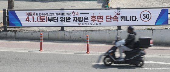 차량의 후면 번호판을 찍어 교통 법규 위반 행위를 적발하고 과태료를 부과하는 방식의 후면 무인교통단속장비가 4월 1일부터 본격적으로 가동에 들어갔다. 후면 무인교통단속장비는 추적용 카메라의 영상 분석 기술을 이용해 차량의 속도위반, 신호위반 등을 감지하고 위반 차량의 후면번호판을 촬영할 수 있어 사륜차뿐만 아니라 이륜차의 교통법규 위반행위도 단속할 수 있다.  사진은 지난 3월 30일 오후 경기 수원시의 한 거리에 후면 단속을 알리는 현수막이 붙어있다. 뉴스1