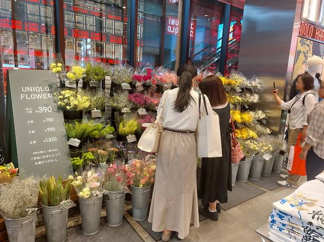 19일 일본 도쿄 하라주쿠 유니클로 매장에서 사람들이 꽃을 구경하고 있다./사진=정인지 기자