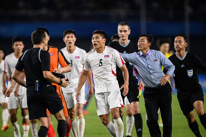 10월 1일 중국 항저우에서 열린 2022 항저우 아시안게임 축구 남자 8강전 북한과 일본의 경기가 끝나고 북한의 김경석(가운데)이 심판에게 달려들며 항의하고 있다./AFP 연합뉴스