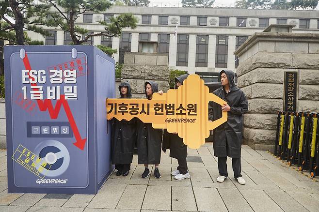 그린피스 기후 공시 헌법소원에 참여하는 시민소송단이 헌법재판소 앞에서 기후 공시 헌법소원 열쇠를 들어보이는 퍼포먼스를 진행하고 있다. [그린피스 제공]