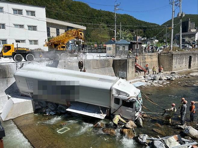 Emergency personnel try to extract a 15-ton truck from the scene of an accident in Jeongseon-gun, Gangwon Province, Thursday. (Gangwon State Fire Headquarters)