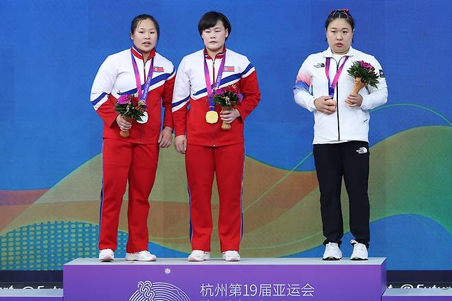 5일 중국 항저우 샤오산 스포츠센터에서 열린 항저우 아시안게임 역도 여자 76kg급 그룹 A 경기에서 동메달을 차지한 대한민국 김수현(오른쪽)이 시상식에서 금메달 북한 송국향(가운데), 은메달 북한 정춘휘와 함께 기념촬영을 하기 위해 함께 시상대에 올라 있다. [사진 출처=연합뉴스]