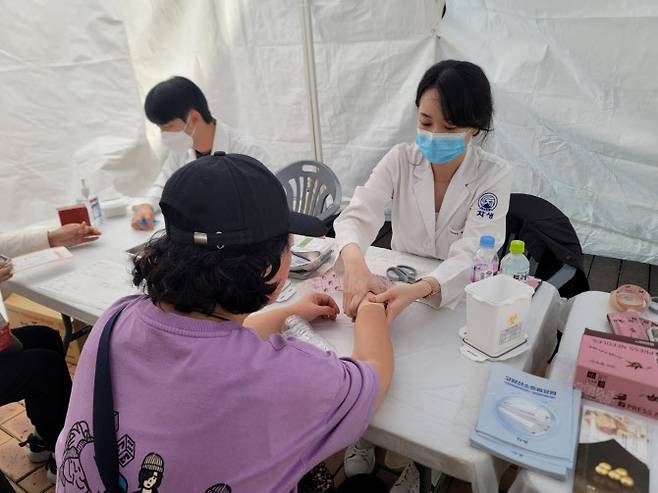 자생한방병원 의료진이 강남구 건강걷기 행사 참가자에게 건강상담 및 테이핑을 진행하고 있다.