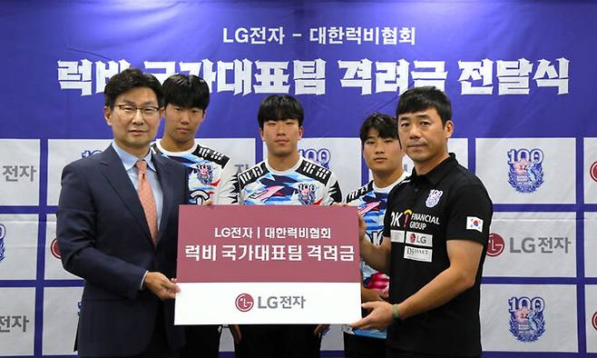 LG전자 한국영업본부장 김영락 부사장(왼쪽)이 지난 11일 서울 중구 대한상공회의소 대한럭비협회 대회의실에서 열린 럭비 국가대표팀 이명근 감독(오른쪽)과 선수들에게 격려금을 전달한 뒤 기념촬영을 하고 있다. LG전자 제공