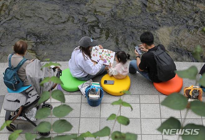 [서울=뉴시스] 김금보 기자 = 13일 서울 중구 청계천에 마련된 '책읽는 맑은냇가' 서울야외도서관을 찾은 시민들이 독서하며 휴식하고 있다. 서울도서관은 오는 15일까지 청계천 청계광장~모전교~광통교 구간에 책바구니를 비치하고 독서 구역으로 구성해 야외도서관으로 운영한다. 2023.10.13. kgb@newsis.com