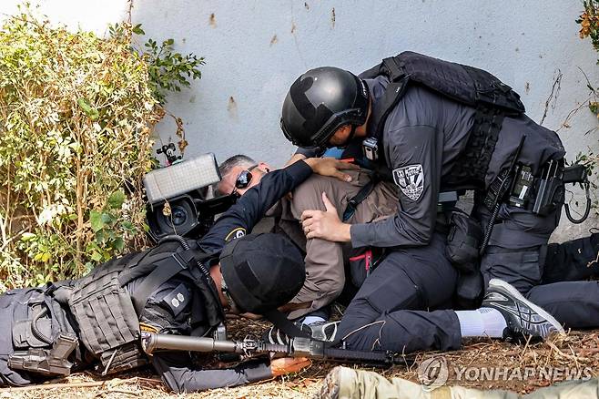 하마스 공습 속 취재기자 보호하는 이스라엘 경찰 (스데로트[이스라엘] AFP=연합뉴스) 이스라엘 군경이 12일(현지시간) 가자지구와 가까운 남부 도시 스데로트에서 공습경보가 울리는 동안 한 취재기자를 보호하고 있다. 지난 7일 팔레스타인 무장 정파 하마스의 이스라엘 기습으로 전쟁이 발발해 양측에서 2천500명 이상이 숨졌다. 2023.10.12 besthope@yna.co.kr