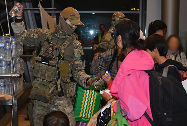 공군 공정통제사들이 공군 KC-330 탑승에 앞서 우리 교민들에게 필요한 물품을 나눠주고 있다. [사진 = 연합뉴스]