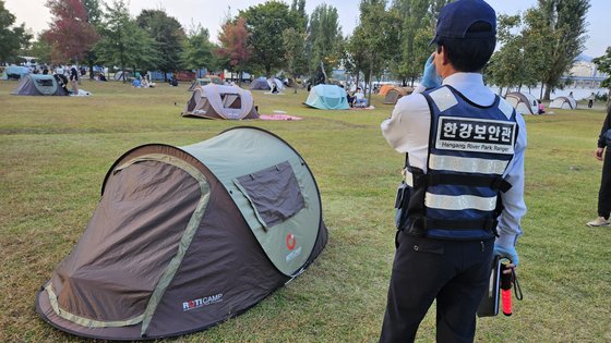 12일 오후 4시 30분쯤 서울 여의도 한강공원에서 단속반 보안관들이 출입문이 모두 닫힌 텐트를 향해 ″2면 이상 개방해주세요″라고 말하며 단속을 실시하고 있다. 장서윤 기자