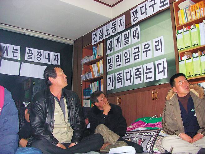 임금체불로 투쟁 중인 전국건설노동조합 조합원들이 노조 사무실에 붙인 항의 문구를 바라보는 모습. 건설노조 제공