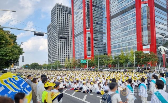 ‘전 세계 구국기도회’라고 적힌 노란 모자를 맞춰 쓴 JMS 신도들이 여의대로 바닥에 앉아 집회에 참석하고 있다. 조승현 기자