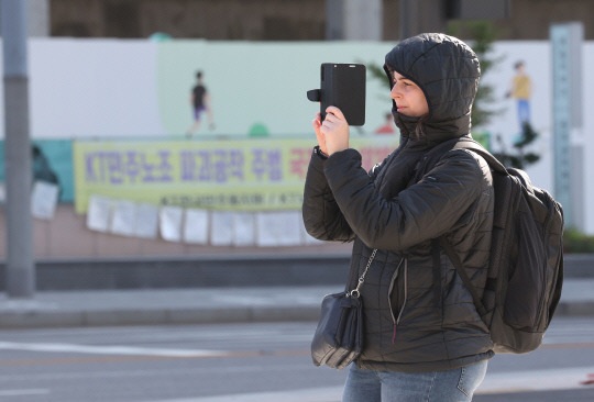 낮과 밤의 기온 차가 10~15도로 예상돼 쌀쌀한 가을 날씨를 보인 16일 오전 서울 종로구 광화문광장에서 한 외국인 관광객이 사진을 찍고 있다. [연합뉴스]