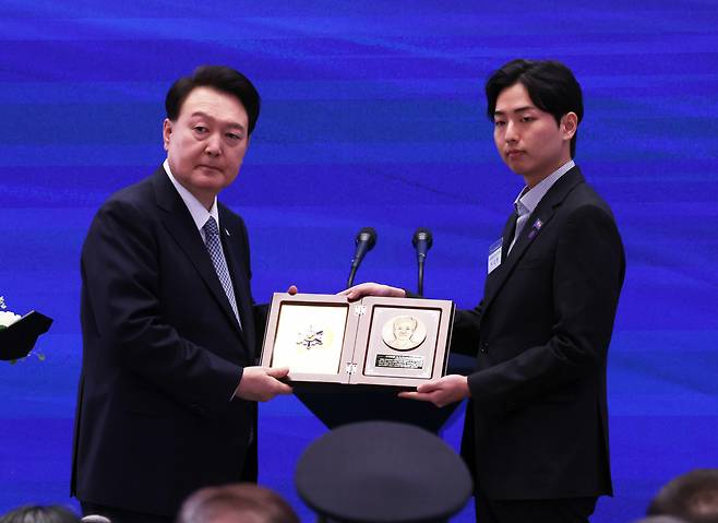 윤석열 대통령이 18일 청와대 영빈관에서 열린 제78주년 경찰의날 기념식에서 순직한 고 이종우 경감의 유가족에게 '경찰 영웅패'를 수여하고 있다. [연합]