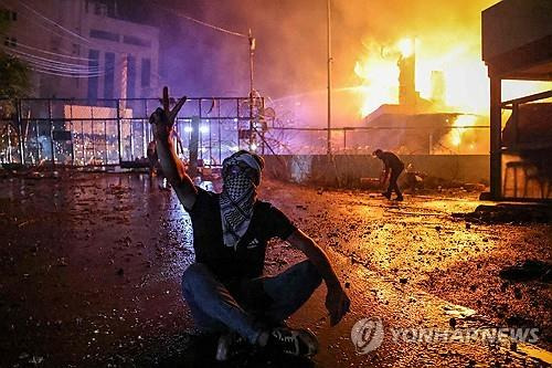 (베이루트 AFP=연합뉴스) 18일(현지시간) 새벽 레바논 베이루트 외곽에 있는 미국 대사관 인근에서 한 시위대가 승리를 의미하는 V자를 그리고 있다. 2023.10.18.