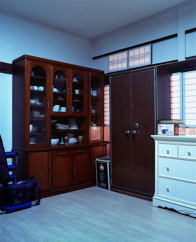 사직작가 오석근의 〈적산 광주(光州) 04〉. 오 작가는 일본식 상가주택(적산가옥)에 담긴 한국인들의 삶을 포착한 작업을 이어왔다. 이 사진은 광주 시내에서 일식 주택의 원형이 가장 잘 남아 있는 집으로 일식주택의 특징인 도코노마(床の間)는 사라져 없어졌지만 란마(欄間), 쇼지(障子) 등은 사진 속 가구, 진열장 뒤로 볼 수 있다. 본래 쇼지(障子)를 열면 남쪽에 위치한 일식 정원을 바라볼 수 있고 동서로 이동할 수 있는 복도가 나오지만 더 이상 그 용도로 사용하지 않고 물건을 진열하고 보관하는 창고로 방을 사용하고 있다. [오석근 작가 제공]