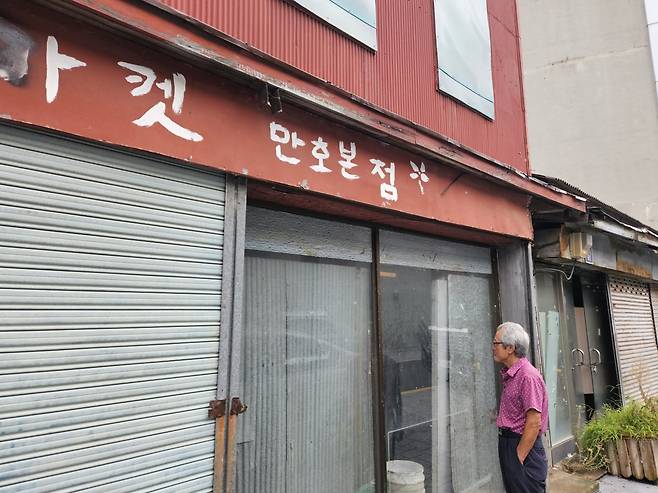 56년동안 목포 번화로에서 일한 김병진(77) 씨가 한때 자신이 일했던 일본식 상가주택(적산가옥)을 바라보고 있다. 김씨가 일했던 건물은 국가등록문화재로 지정됐지만 몇 년 째 비어있다. 목포=김빛나 기자