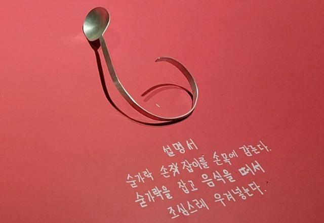 서울문화재단이 서초구 예술의전당 한가람미술관에서 연 장애예술기획전 '내가 사는 너의 세계'전에 나온 라움콘 작가의 '한 손 젓가락, 숟가락 그리고 포크'가 붉은색 테이블 위에 관람객의 착용을 권하는 문구와 함께 전시된 모습. 김청환 기자