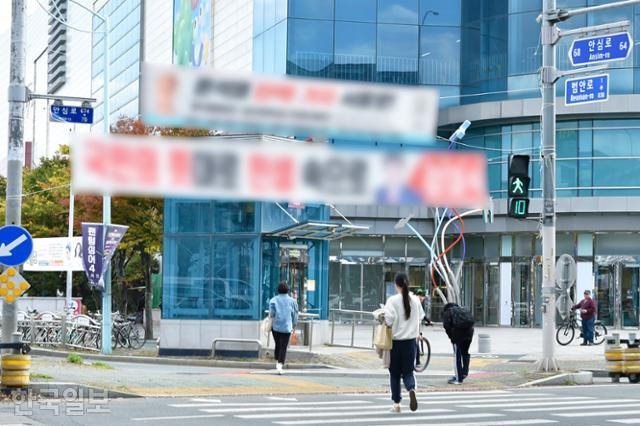 시민들이 21일 오후 대구 동구 율하동 한 교차로에 붙은 정당 현수막 아래의 횡단보도를 건너고 있다. 류수현 기자