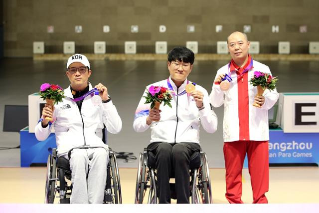 이장호(가운데)와 박진호(왼쪽)가 23일 중국 항저우 푸양 인후 스포츠센터에서 열린 2022 항저우 장애인 아시안경기대회 사격 R1(SH1 남자 10ｍ 공기소총 입사) 시상식에서 각각 금메달과 동메달을 들어보이고 있다. 대한장애인체육회 제공