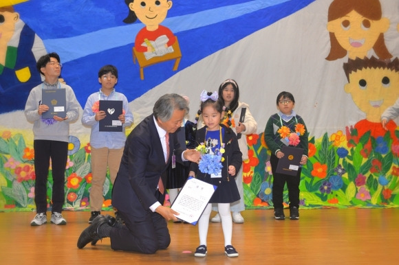 인간성회복추진협의회(인추협) 주최로 10월 21일 서울 여의도 국회의원회관 대회의실에서 열린 ‘2023 사랑의 일기 큰잔치 세계대회 시상식’에서 고진광 인추협 이사장이 수상자 학생의 키에 맞춰 무릎을 꿇고 상을 수여하고 있다.  인추협 제공