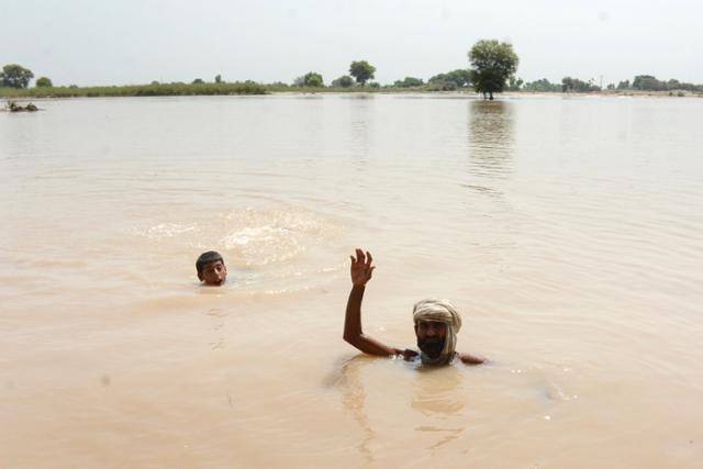 지난달 7일 폭우로 파키스탄 펀자브주 로드란 인근 수틀레지강이 범람해 주민들의 목까지 물이 차 있다. 로드란=EPA 연합뉴스