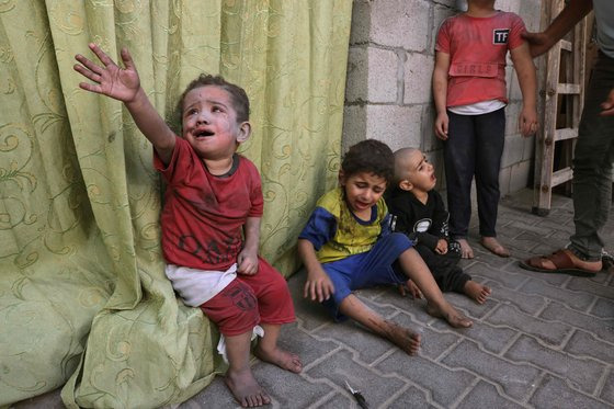 이스라엘 공습으로 인한 먼지로 뒤덮인 팔레스타인 어린이들이 가자지구 한 병원 앞에 앉아 있다. AFP=연합뉴스