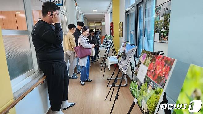 충북 영동 심천초등학교에서 열린 사진작품 전시회를 찾은 학부모들이 작품을 감상하고 있다. (심천초 제공) /뉴스1