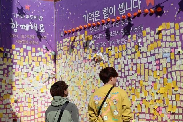 이태원 참사 1주기를 앞둔 27일 시민들이 서울 용산구 이태원역 1번 출구 앞 골목 초입 마련된 추모공간의 추모의 글을 살펴보고 있다. 뉴스1