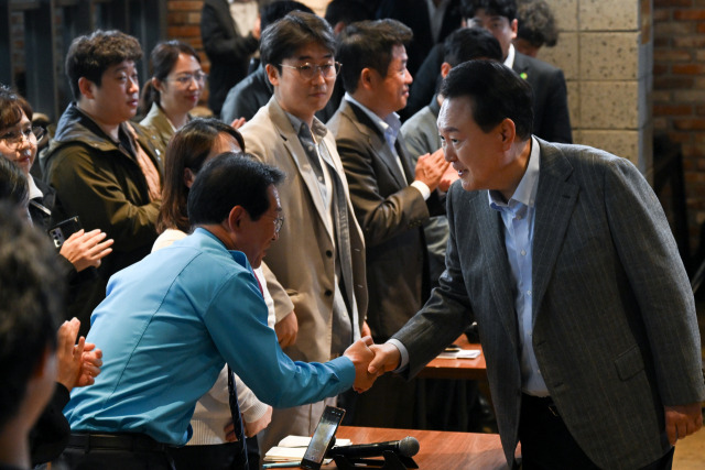 윤석열 대통령이 1일 서울 마포구 한 카페에서 비상경제민생회의를 열고 카카오택시의 수수료 문제점 등을 하소연한 택시운전기사 김호덕(왼쪽)씨와 악수하고 있다. 사진 제공=대통령실