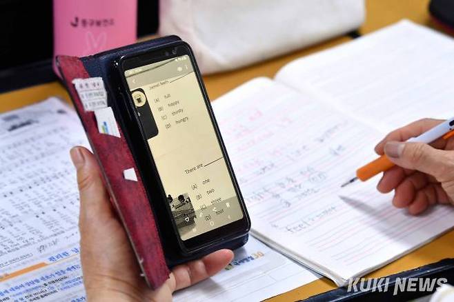 한 어르신 학생이 스마트 폰을 활용해 영어 단어를 확인하고 있다.