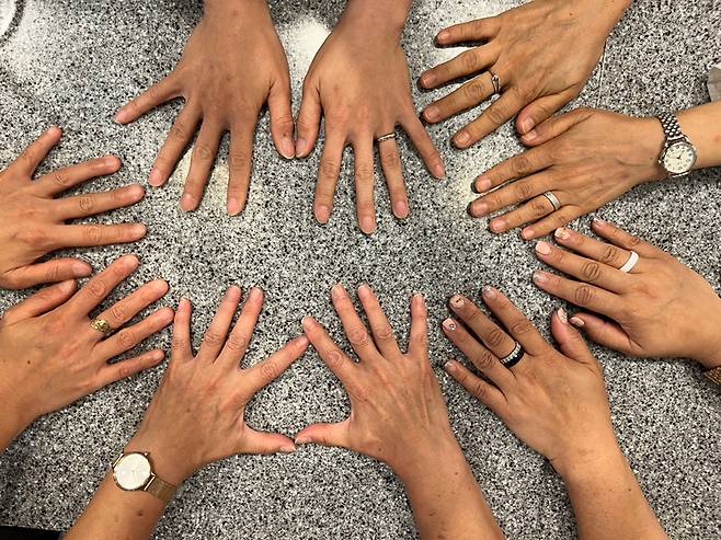 Korea-born adoptees adopted in Korea and overseas put their hands together on a cafe table where they met to hear more from a birth mother and share their experiences in Seoul on July 21. [ESTHER CHUNG]