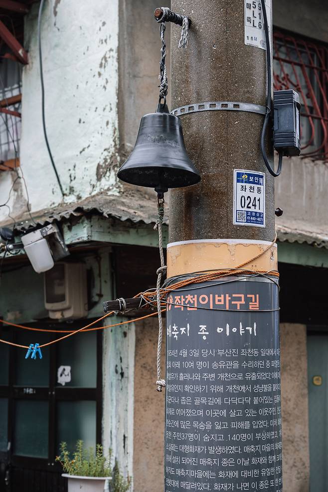 마을 전봇대에 달린 화재 경보종. 좁은 골목길에 다닥다닥 집들이 붙어있어 마을 사람들은 이 종을 통해 화재 소식을 알렸다. '수호 종'이라는 별칭도 붙었다.