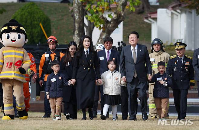 [서울=뉴시스] 전신 기자 = 윤석열 대통령과 부인 김건희 여사가 9일 서울 용산어린이정원 잔디마당에서 열린 제61주년 소방의 날 기념식에 순직 소방관 자녀들과 손을 잡고 함께 입장하고 있다. 2023.11.09. photo1006@newsis.com