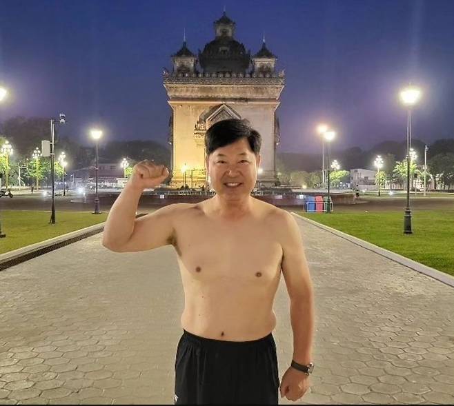 이만수 전 SK 감독이 라오스 비엔티안의 대통령궁 앞에서 상의를 탈의한 채 주먹을 불끈 쥐어 보이고 있다. 이 전 감독은 라오스 야구 대표팀의 항저우 아시안게임 첫 승 공약을 지켰다. 헐크파운데이션 제공