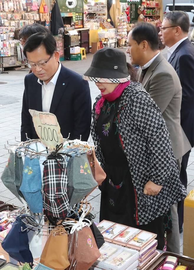 지난 8일 서울 중구 남대문시장을 방문한 조병규 우리은행장(왼쪽)이 상인들과 간담회를 마치고 물건을 구입하기 위해 한 가게를 둘러보고 있다. 우리은행 제공