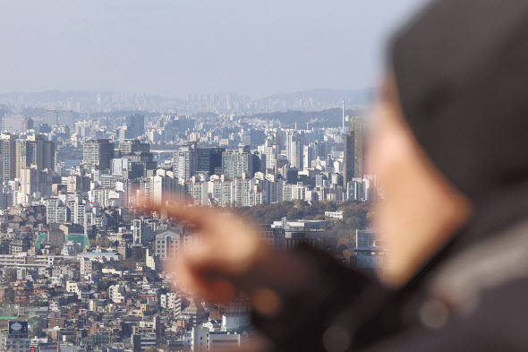 12일 한 시민이 남산에서 서울 시내 아파트를 가리키고 있다. [연합]